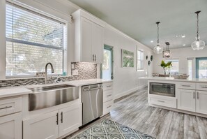 A spacious kitchen with white cabinetry, a stainless steel sink, and a dishwasher. - Steps to the beach- Heated Pool- Golf Cart-Hot Tub- Beach Service- Bikes  (Destin)