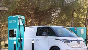 A white electric vehicle charging at a station labeled "ELECTRA" with numbers "03 04" on it.