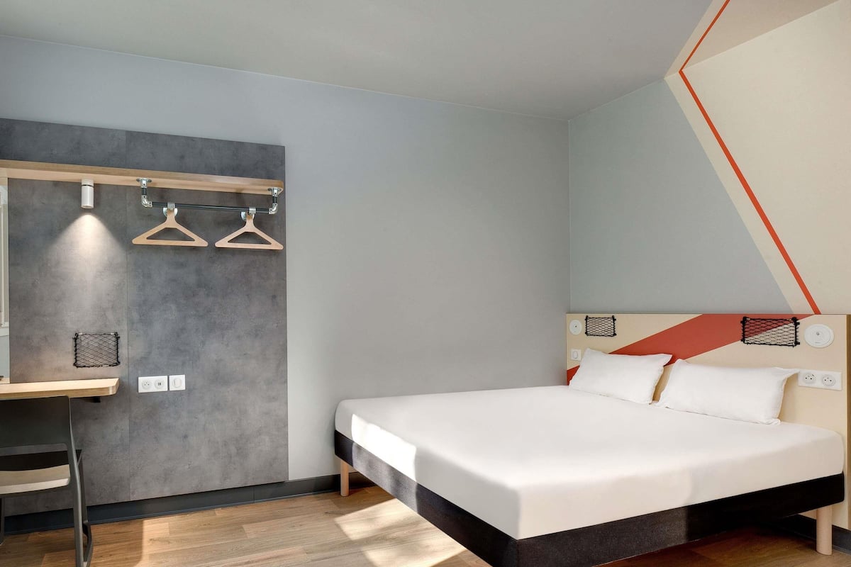 Une chambre d’hôtel moderne équipée d’un lit, d’un bureau et d’un luminaire suspendu.
