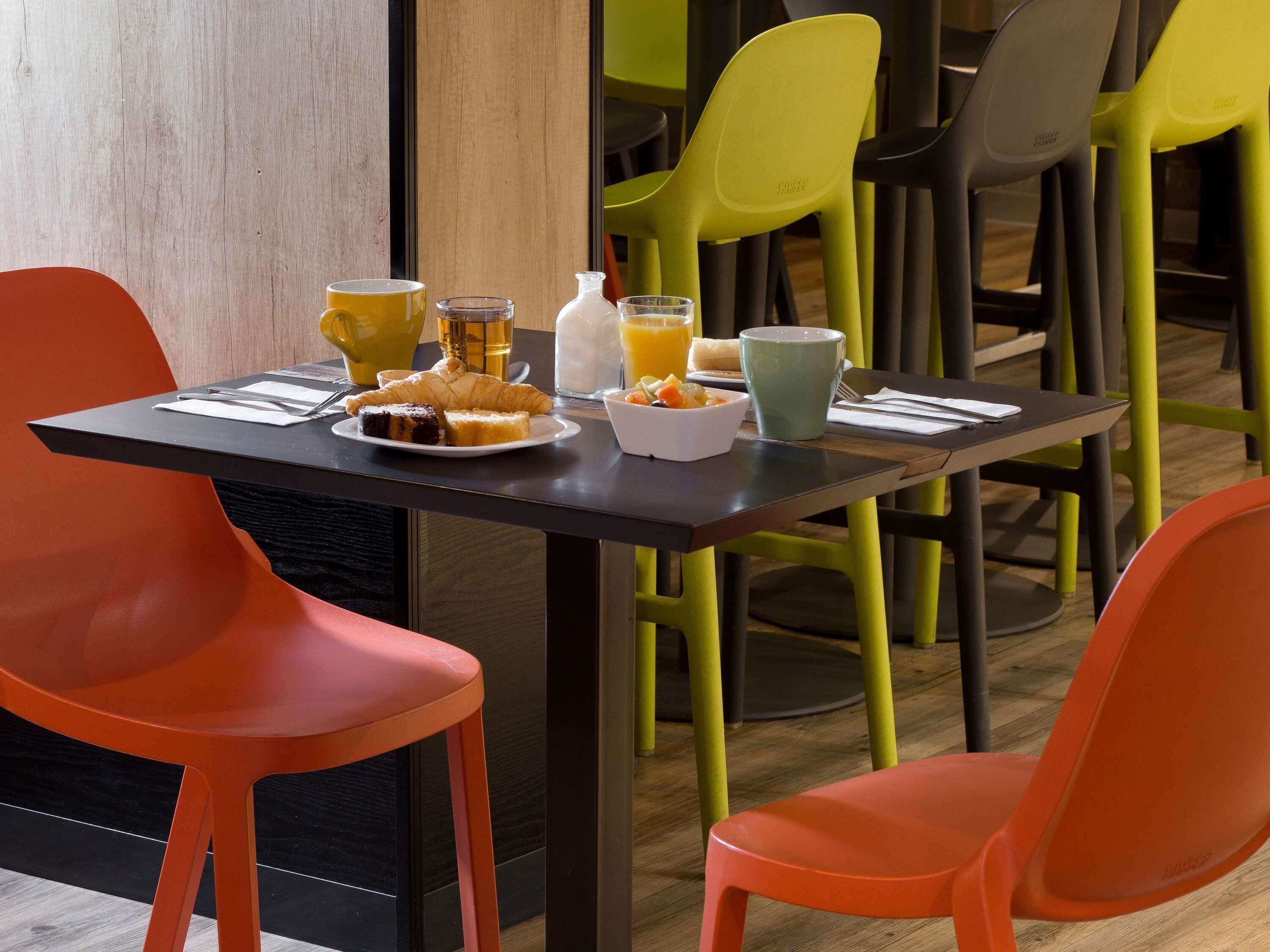Una mesa de desayuno con un croissant, jugo y una taza de café.