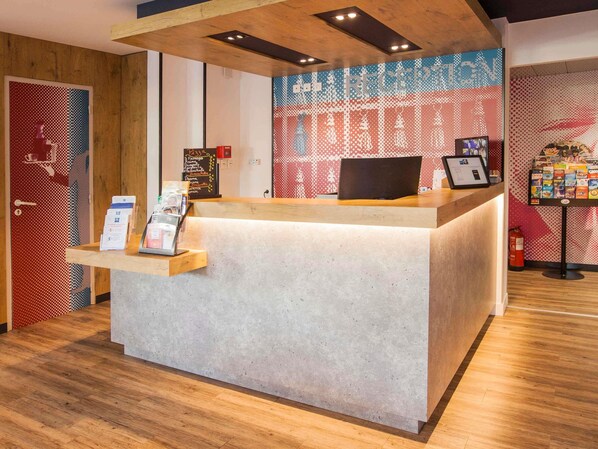 A reception desk with a digital screen, a wooden counter, and a wall with a patterned design.