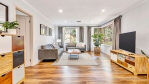 Una sala de estar moderna con un sofá, una mesa de centro, un televisor y un mueble de madera.