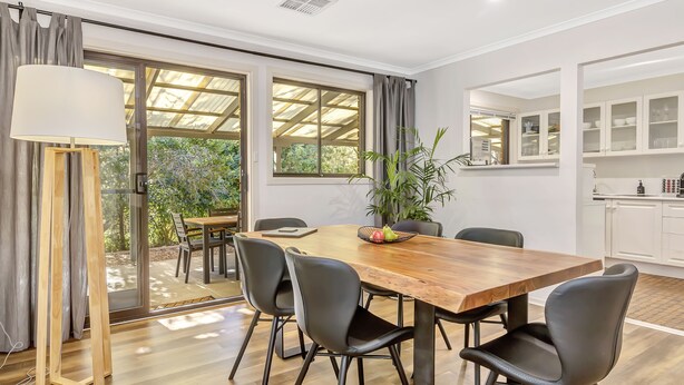 Un comedor con una mesa de madera, sillas negras y una planta en maceta.