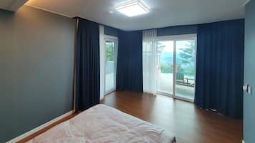 Et soveværelse med en seng, en skydedør til en balkon og udsigt over naturen.