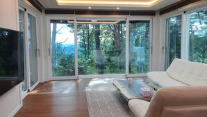 Un salon moderne doté d’une grande porte-fenêtre coulissante qui donne sur un paysage extérieur magnifique.