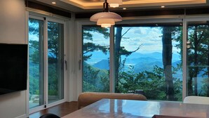 Un espace de restauration moderne, doté d’une grande table, de chaises et offrant une vue sur les montagnes grâce à de larges fenêtres.