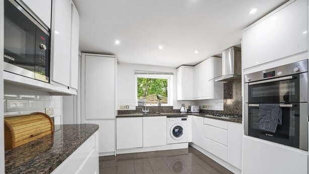 A modern kitchen with white cabinetry, a Bosch washing machine, a built-in oven, and a window providing natural light. - House - Sleeps 8 & On-site Parking (Aylesford)