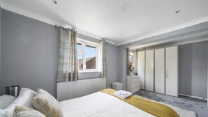A bedroom with a bed, a bedside table, a dresser, a mirror, and a wardrobe. - House - Sleeps 8 & On-site Parking (Aylesford)