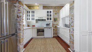 A compact kitchen with white cabinetry, a built-in oven, and a dishwasher. - Aylmerton House + Cottage for 14, Southern Highlands (Mittagong)