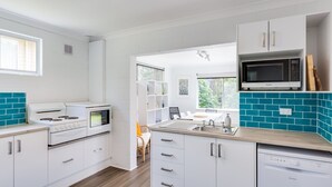 A modern kitchen with white cabinets, a built-in oven, a microwave, and a dishwasher. - Bay Breeze at Blenheim Beach, Vincentia (Vincentia)