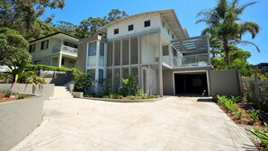 A modern two-story house with a covered driveway, a garage, and a landscaped garden. - Beachdaze at Hyams Beach (Hyams Beach)