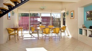 A spacious dining area with a large table and chairs, a staircase, and a view of the outside. - Beachdaze at Hyams Beach (Hyams Beach)