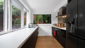 Een moderne keuken met een groot raam, zwarte kastjes en een inbouwoven.
