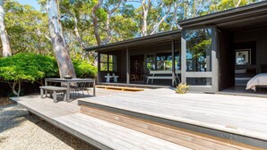 A modern house with a wooden deck, outdoor seating, and a large window overlooking the garden.