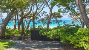 A pathway leading to a wooden gate with a view of the sea and trees.