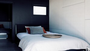 A bedroom with a bed, a window, and a bedside table.