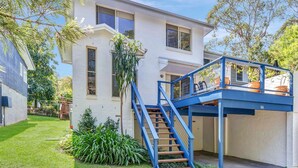 A two-story house with a blue staircase leading to a balcony.
