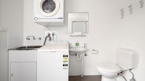 A compact, modern bathroom with a washing machine, sink, and toilet. - Boathouse 1, Hyams Beach (Hyams Beach)