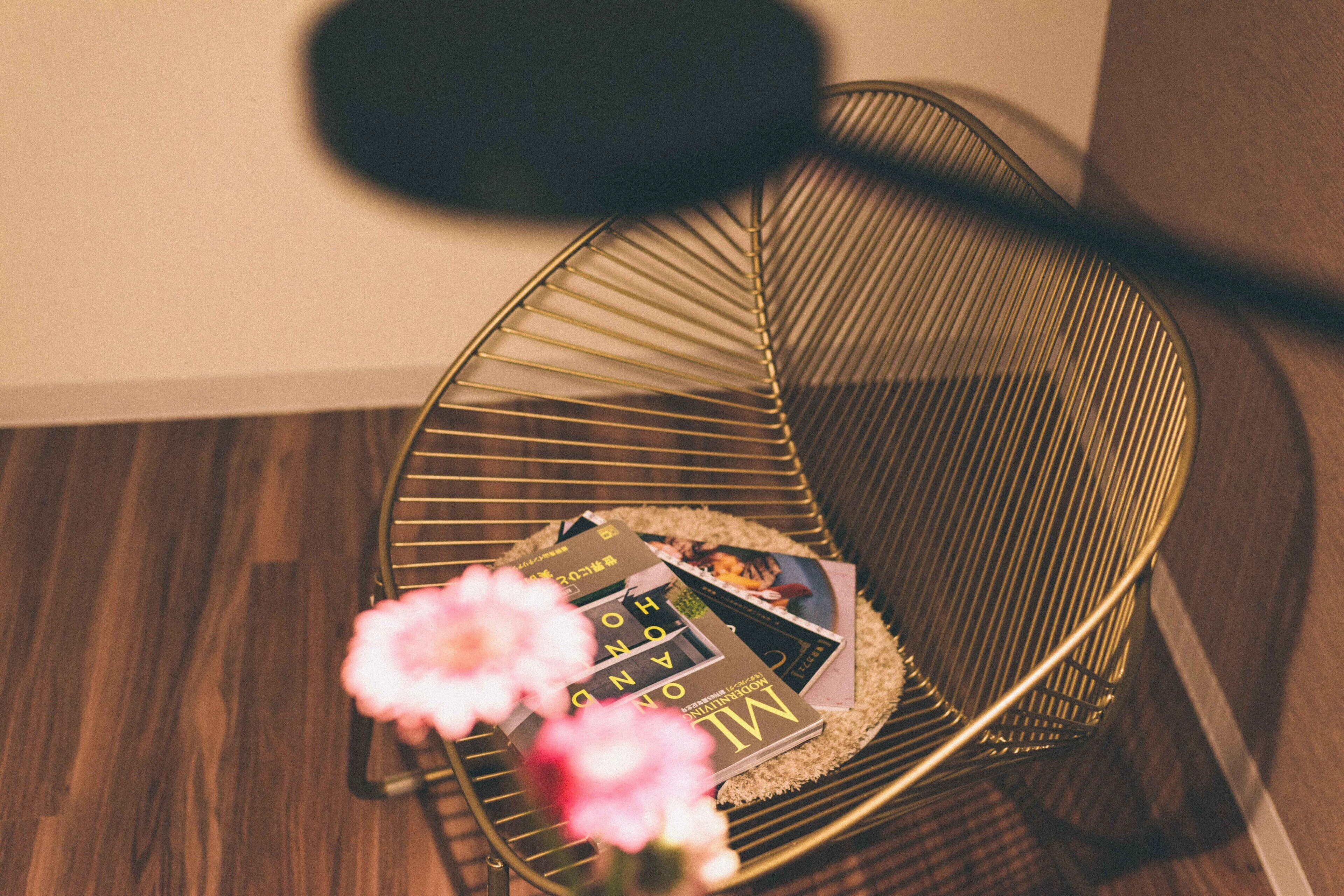Una silla de metal con revistas y flores sobre un piso de madera.