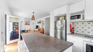 A modern kitchen with white cabinets, a stainless steel refrigerator, a microwave, and a tiled backsplash.