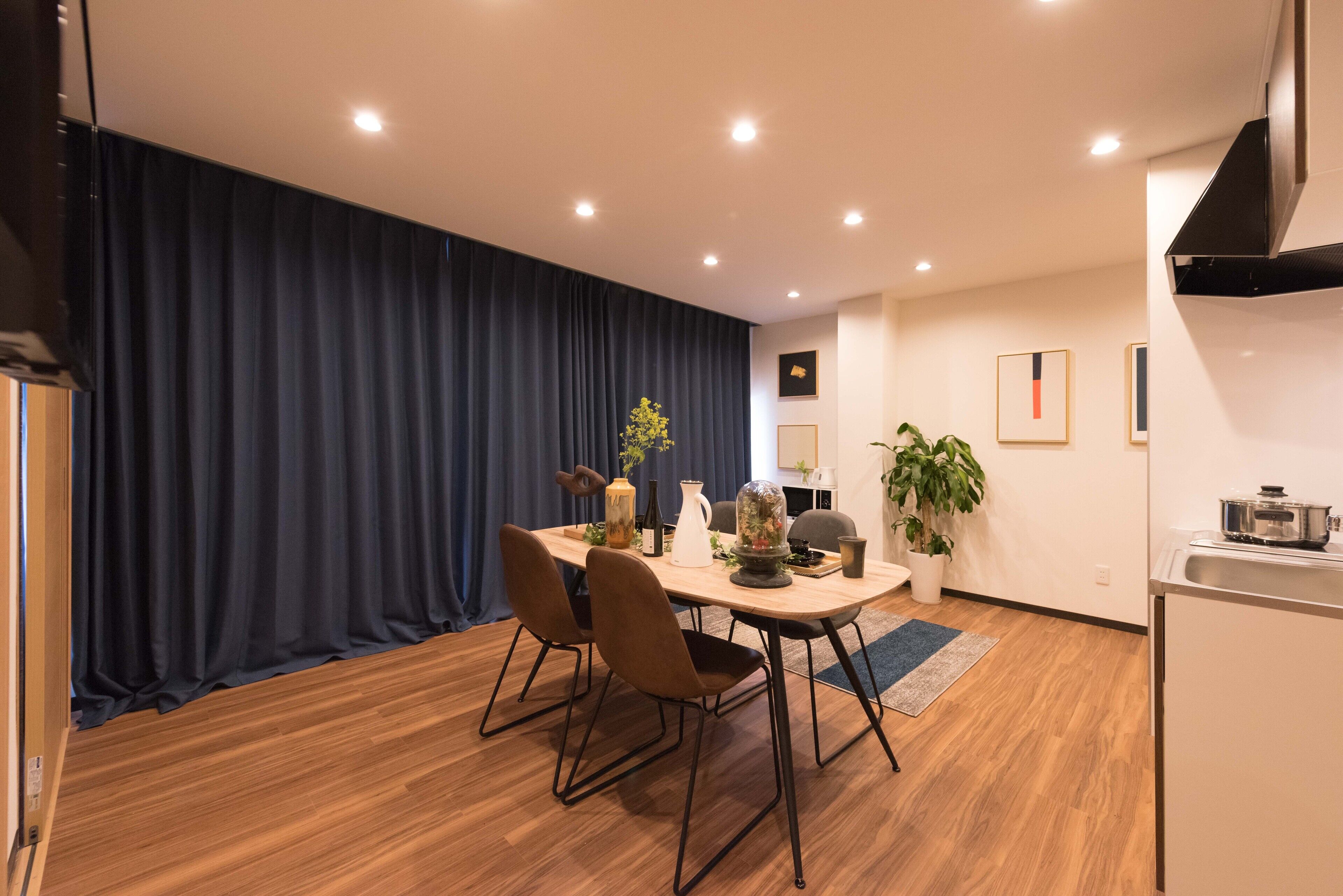 A modern dining area with a wooden table, two chairs, a vase, and a potted plant.