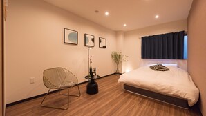 Un dormitorio moderno con cama, una silla, una mesita y decoración en la pared.