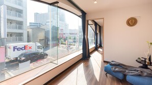 Una habitación de hotel moderna con un ventanal grande, un sofá azul y una pequeña mesa con una planta.
