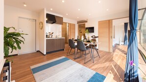 Una cocina moderna con armarios de madera, un comedor con mesa y sillas, y un amplio ventanal con cortinas.