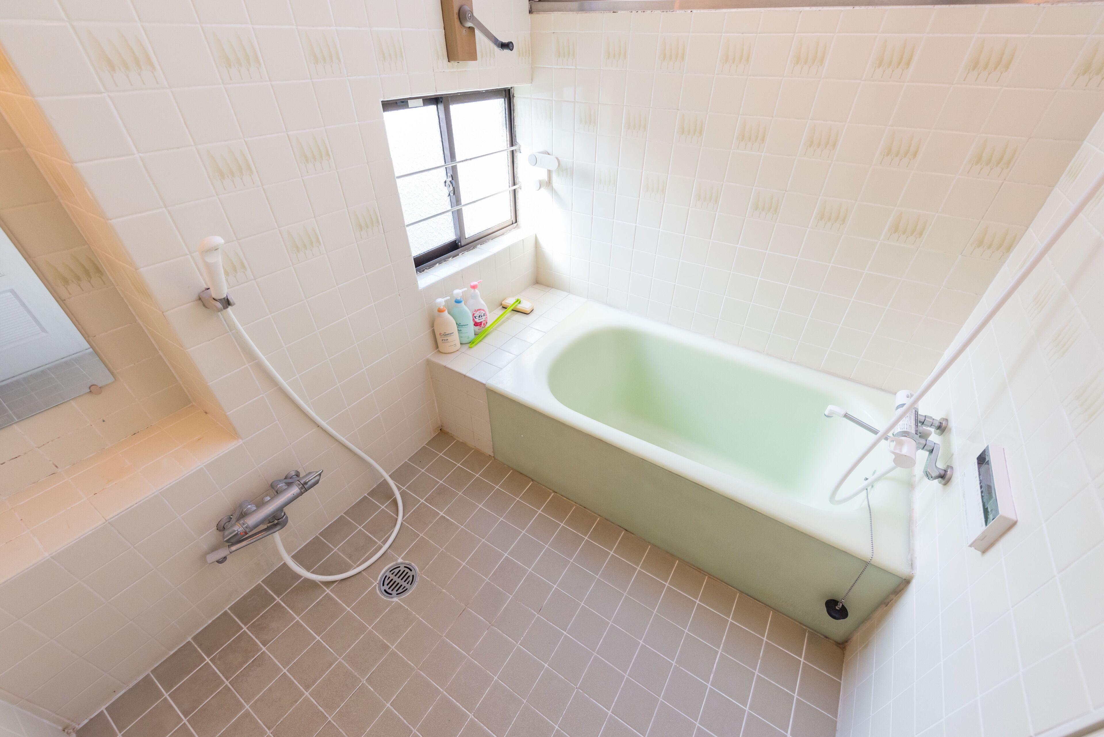 A small bathroom with a bathtub, a window, and a toilet.