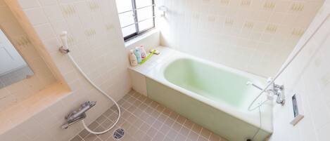A small bathroom with a bathtub, a window, and a toilet.