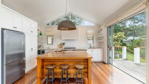 Una cocina moderna con una isla grande, taburetes de bar y vistas al exterior.