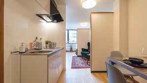A modern kitchen with a built-in stove, sink, and a dining area with a table and chairs. - TORA Hotel Ueno 193D (Tokyo)