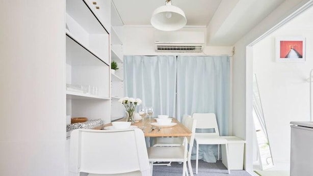 A compact, modern kitchen with white cabinetry, a wooden dining table, and matching chairs. - TORA Hotel Kita Ueno144 (Tokyo)