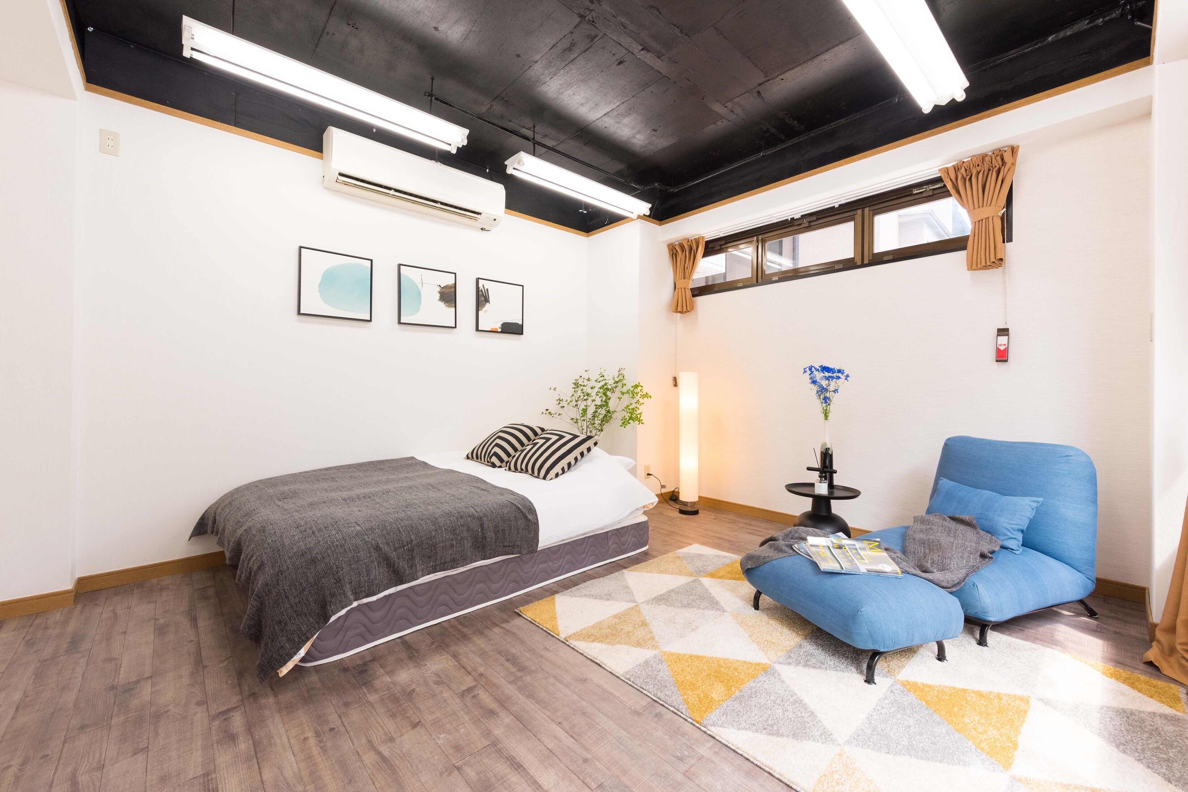 Una habitación moderna con una cama, un sillón azul y una mesita de noche con una lámpara.