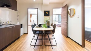 A modern kitchen with a dining area, wooden flooring, and a view of the outdoors. - TORA HOTEL Komagome B (Tokyo)