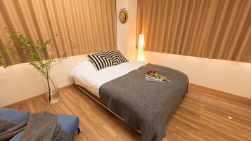 Habitación de hotel impecable con cama, mesita de noche, un florero con planta y ventana con cortinas.