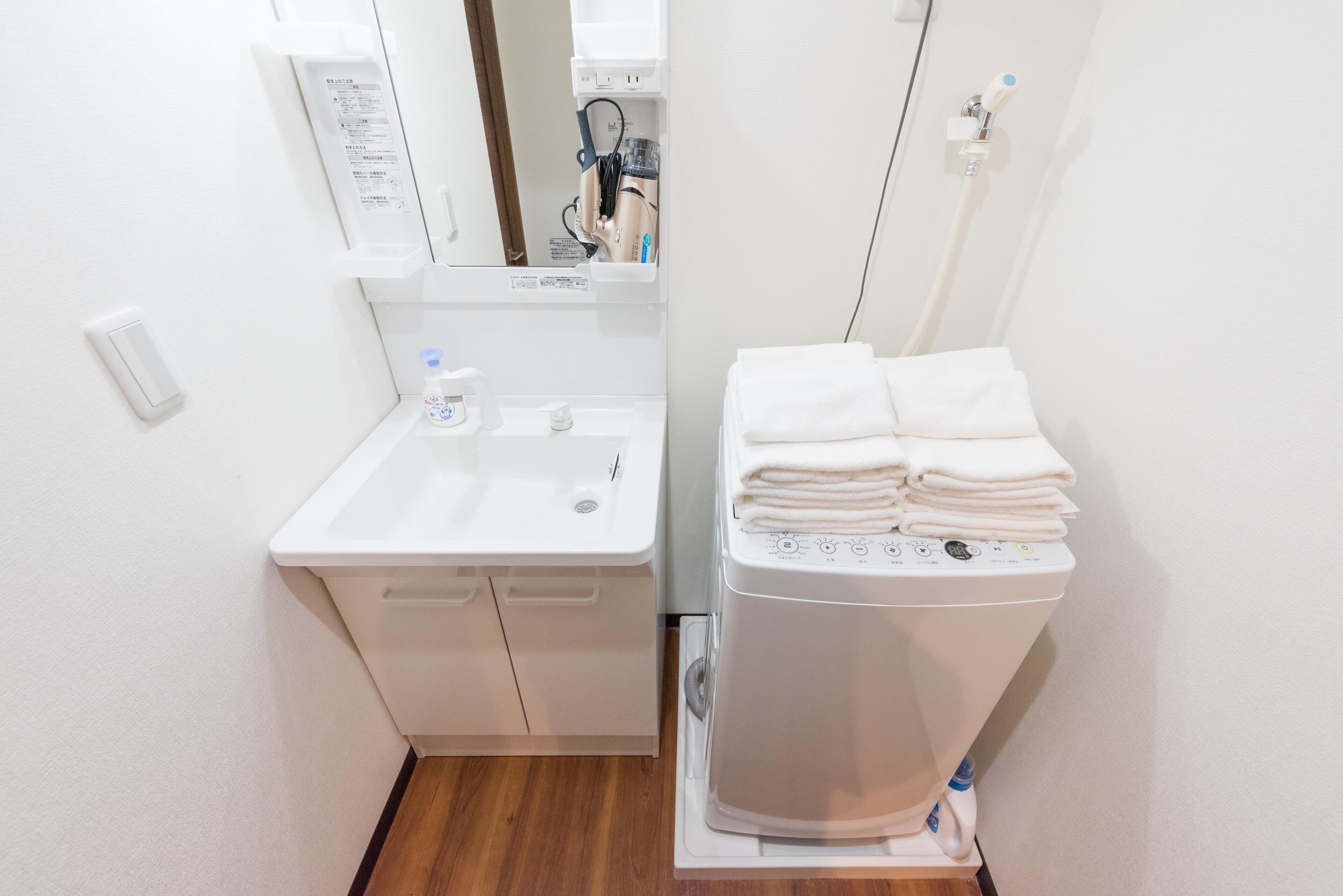 A compact bathroom with a sink, mirror, and stacked towels.