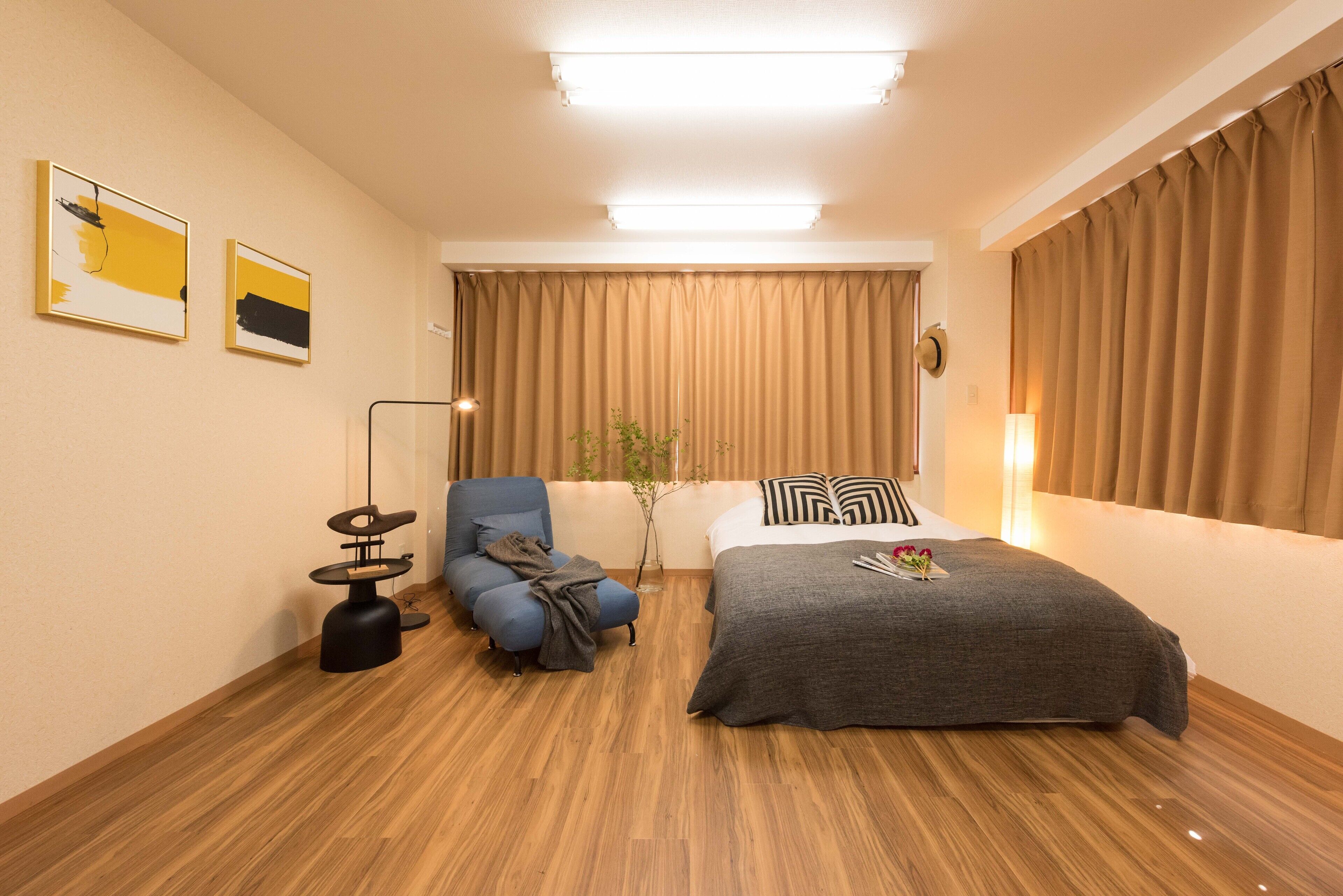 Quarto de hotel moderno com cama, cadeira, escrivaninha e obras de arte nas paredes.