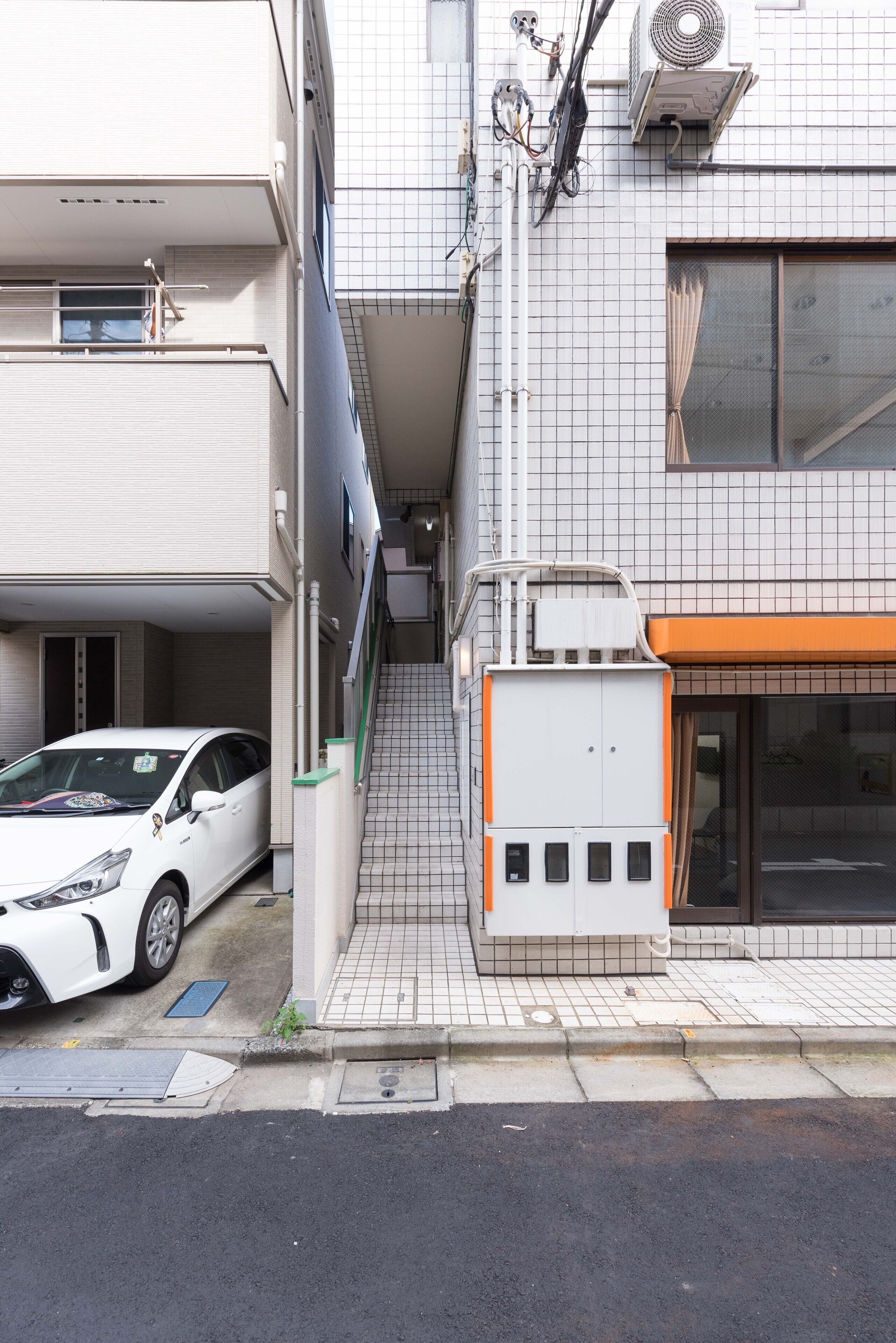 A narrow urban street with a white car parked on the left.