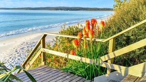 Eine Holztreppe führt zu einem Strand mit freiem Blick auf das Meer.