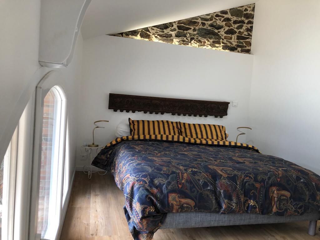 A bedroom with a large bed, a stone accent wall, and a window.