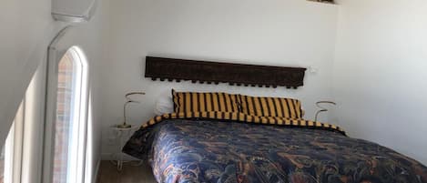 A bedroom with a large bed, a stone accent wall, and a window.