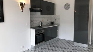Eine kompakte Küche mit dunklen Schränken, einer gefliesten Rückwand und einem modernen Herd.
