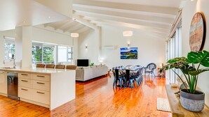 A spacious kitchen with a large island, a dining area with a table and chairs, and a living area with a sofa and TV.