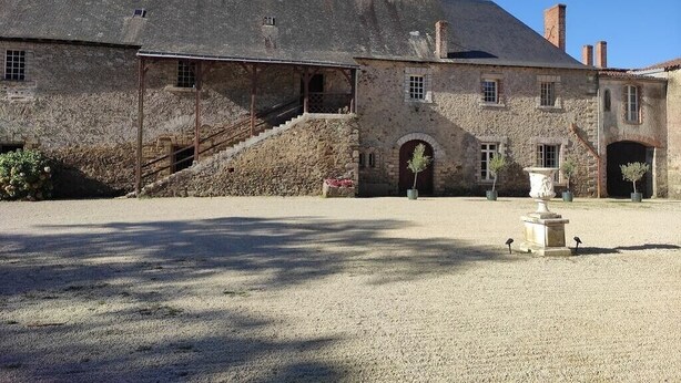A historic stone building with a covered staircase, a courtyard, and a fountain. - Château du Parc Soubise - Gîte Bonfils (Mouchamps)