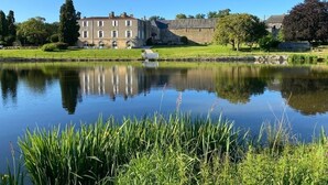 A large stone building with a reflective pond in front. - Château du Parc Soubise - Gîte Bonfils (Mouchamps)