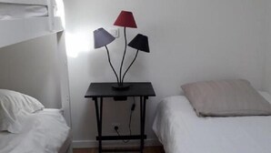 A room with a bed, a small table with a lamp, and a bunk bed. - Château du Parc Soubise - Gîte Bonfils (Mouchamps)