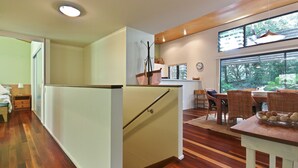 Una cocina moderna con refrigerador empotrado, piso de madera y un comedor con sillas de mimbre y una mesa.