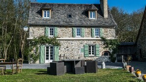A stone house with green shutters, a chimney, and a small window. - Au nid de Caroline (ISSOR)