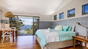 A bedroom with a large bed, a desk, and a view of the sea. - Majestic on Palm Beach, Jervis Bay (Sanctuary Point)